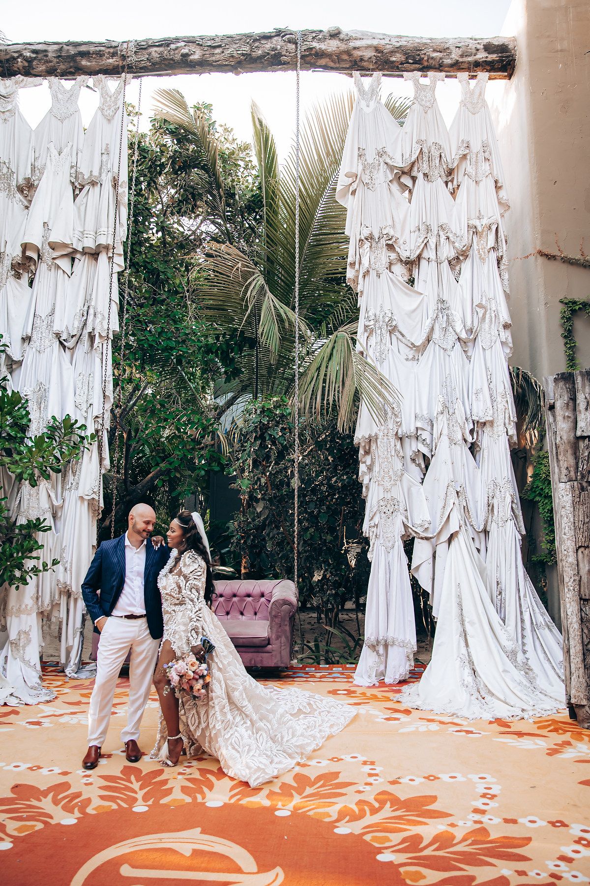 Wedding portrait setup with draped white fabric and rustic wooden beam against tropical foliage.