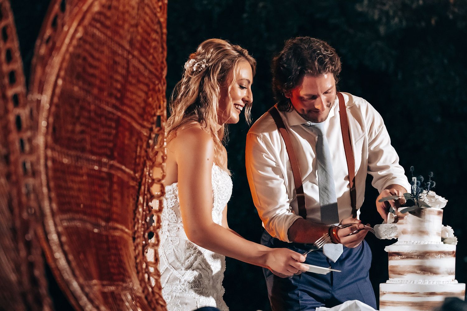 Intimate wedding reception scene with vintage wicker furniture and dark moody lighting.