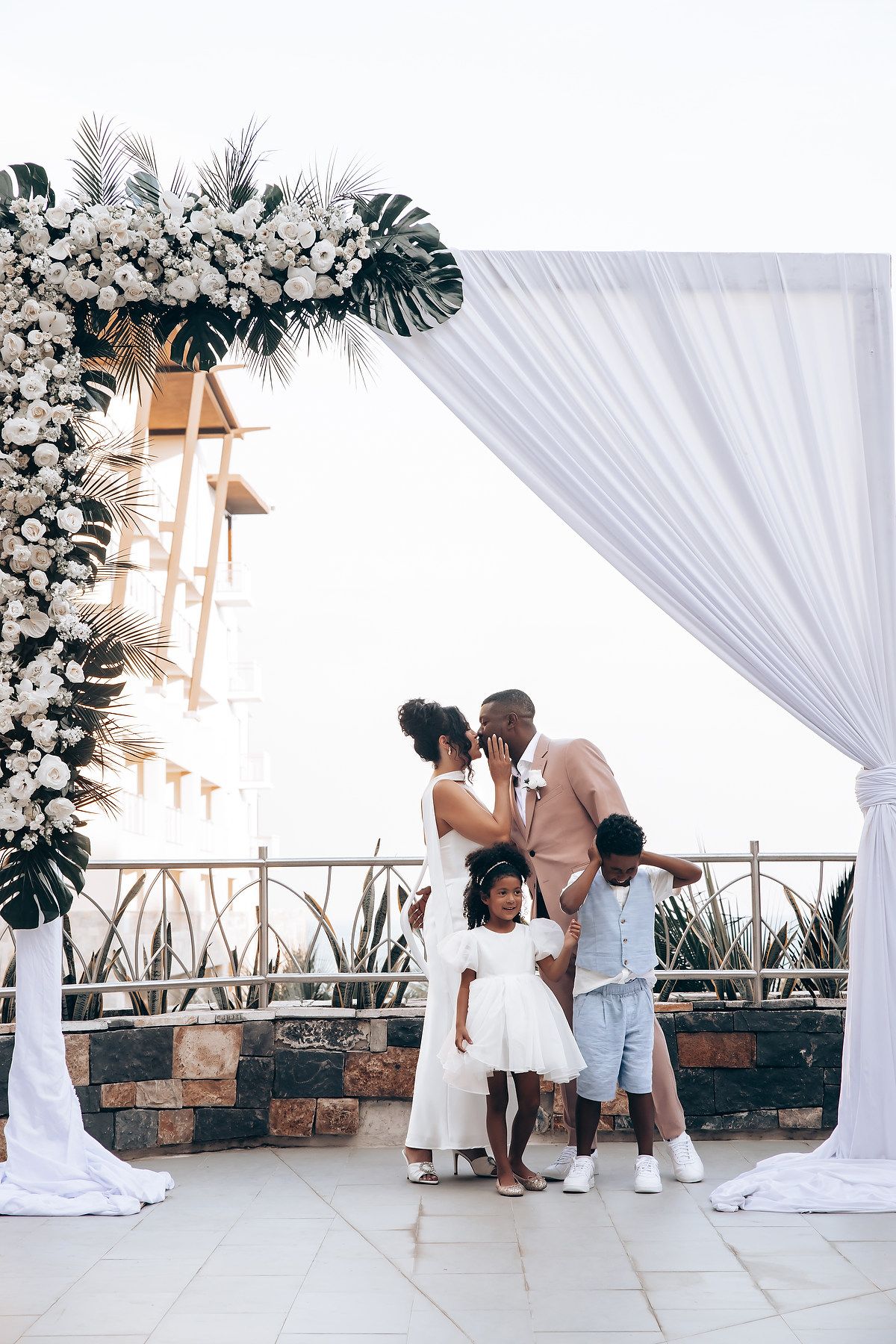 Wedding ceremony setup with white draping and floral arrangements in outdoor venue.