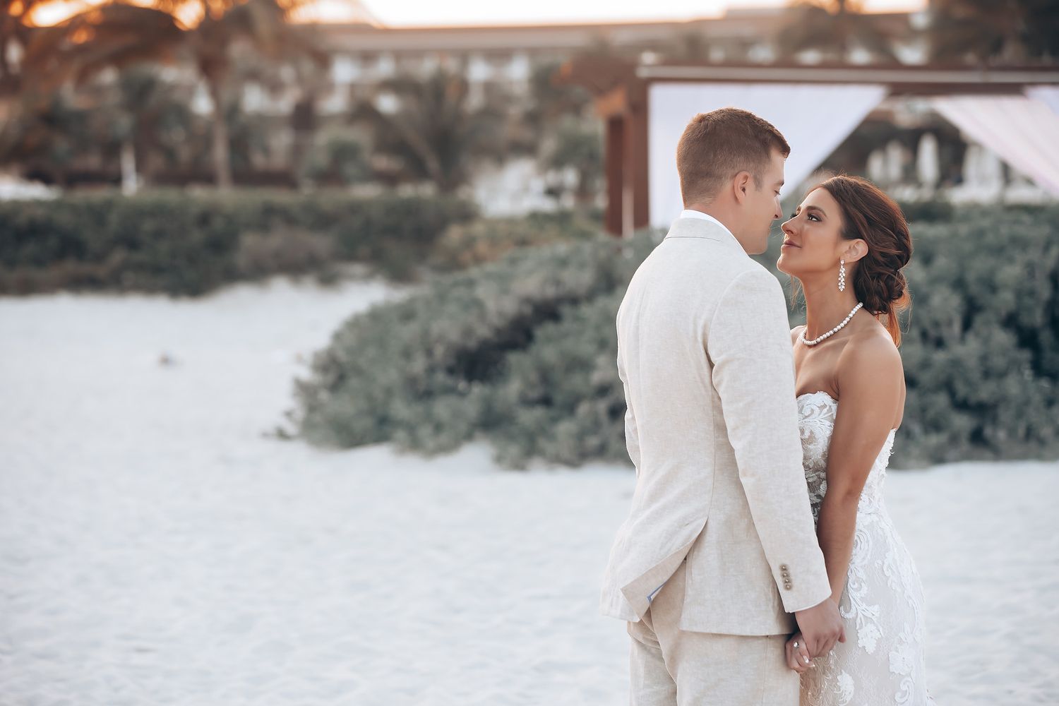 Romantic beachside wedding portraits at sunset with tropical scenery.