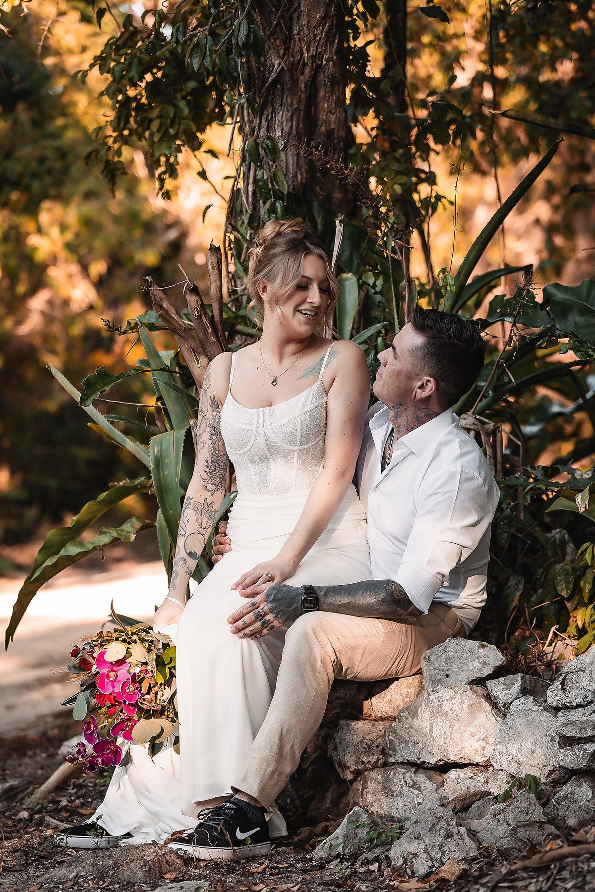 A couple shares a tender moment while seated on natural stone steps in a garden setting.