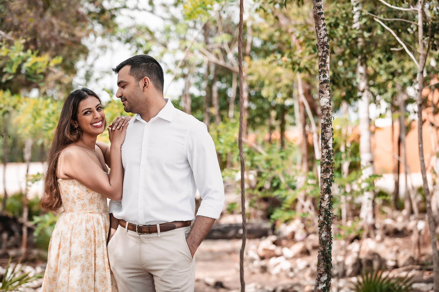 Natural light engagement photos in tropical garden setting with palm trees and pathways.