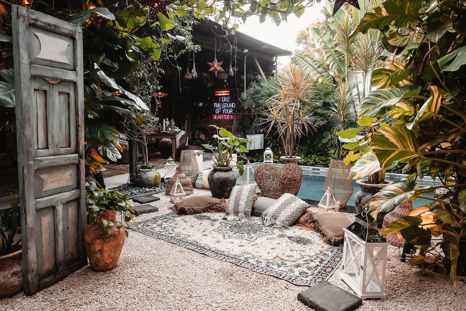 Scenic garden pathway decorated with stones and tropical plants leading to a pool area.