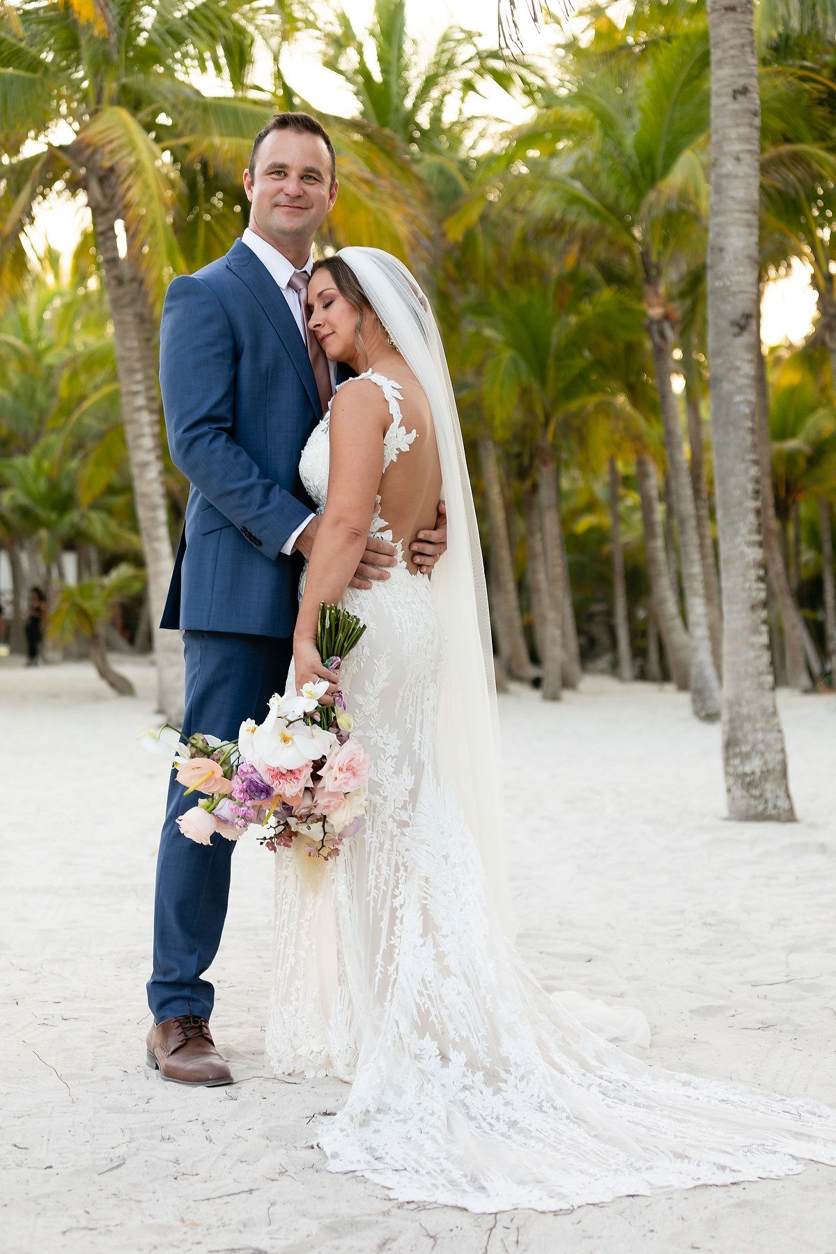 A romantic beach wedding photoshoot with palm trees and white sand creating a tropical paradise backdrop.