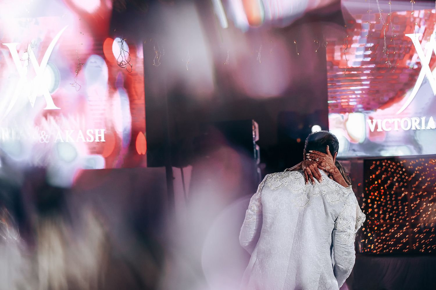 A performer in a white outfit dances energetically on stage with blurred lights and effects in the background.