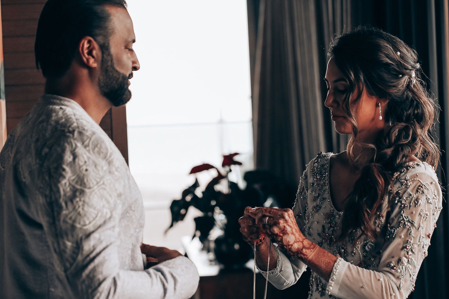 A couple in formal wedding attire share an intimate embrace while holding white roses.