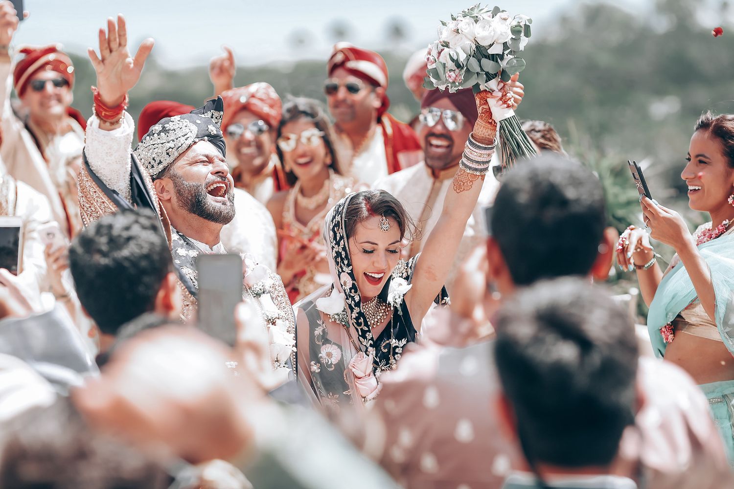 Joyful celebration with confetti flying as crowd cheers during outdoor wedding festivities.