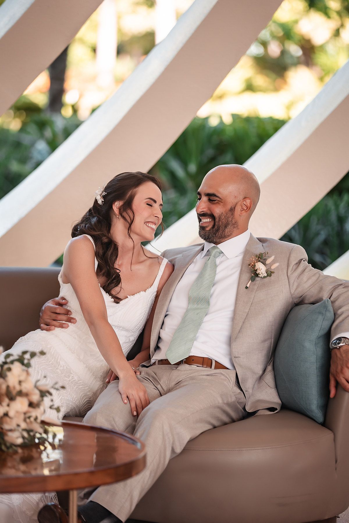 A couple shares an intimate moment while sitting together on a couch during their wedding celebration.