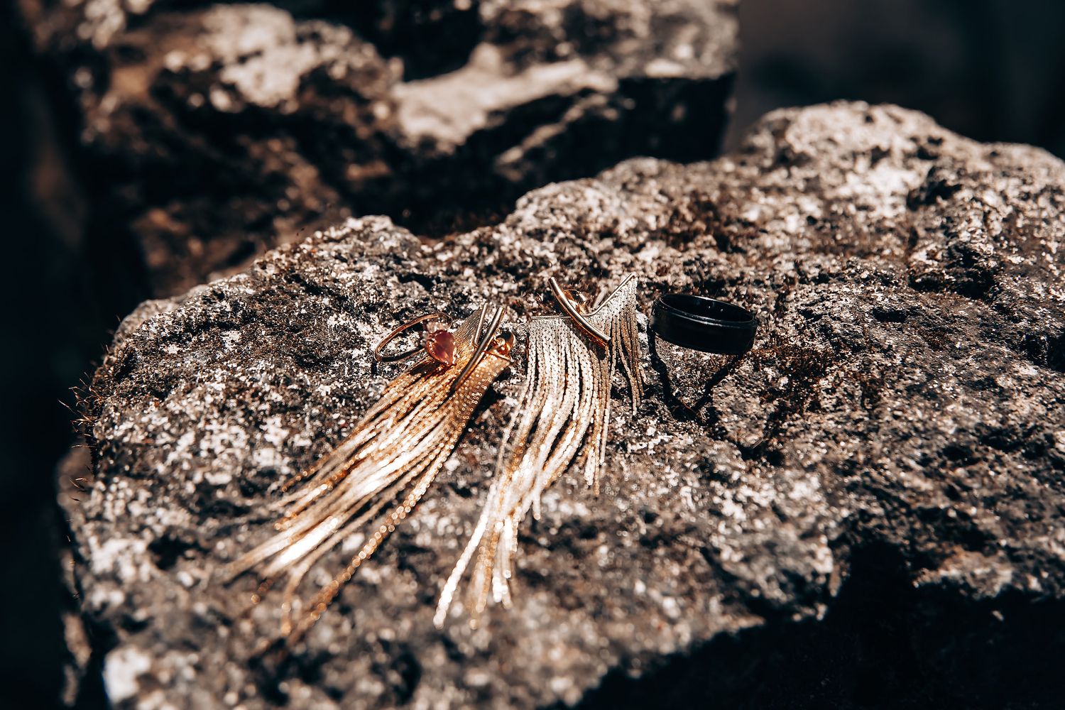 Gold stacking rings with delicate wire-wrapped design displayed on dark textured stone surface.