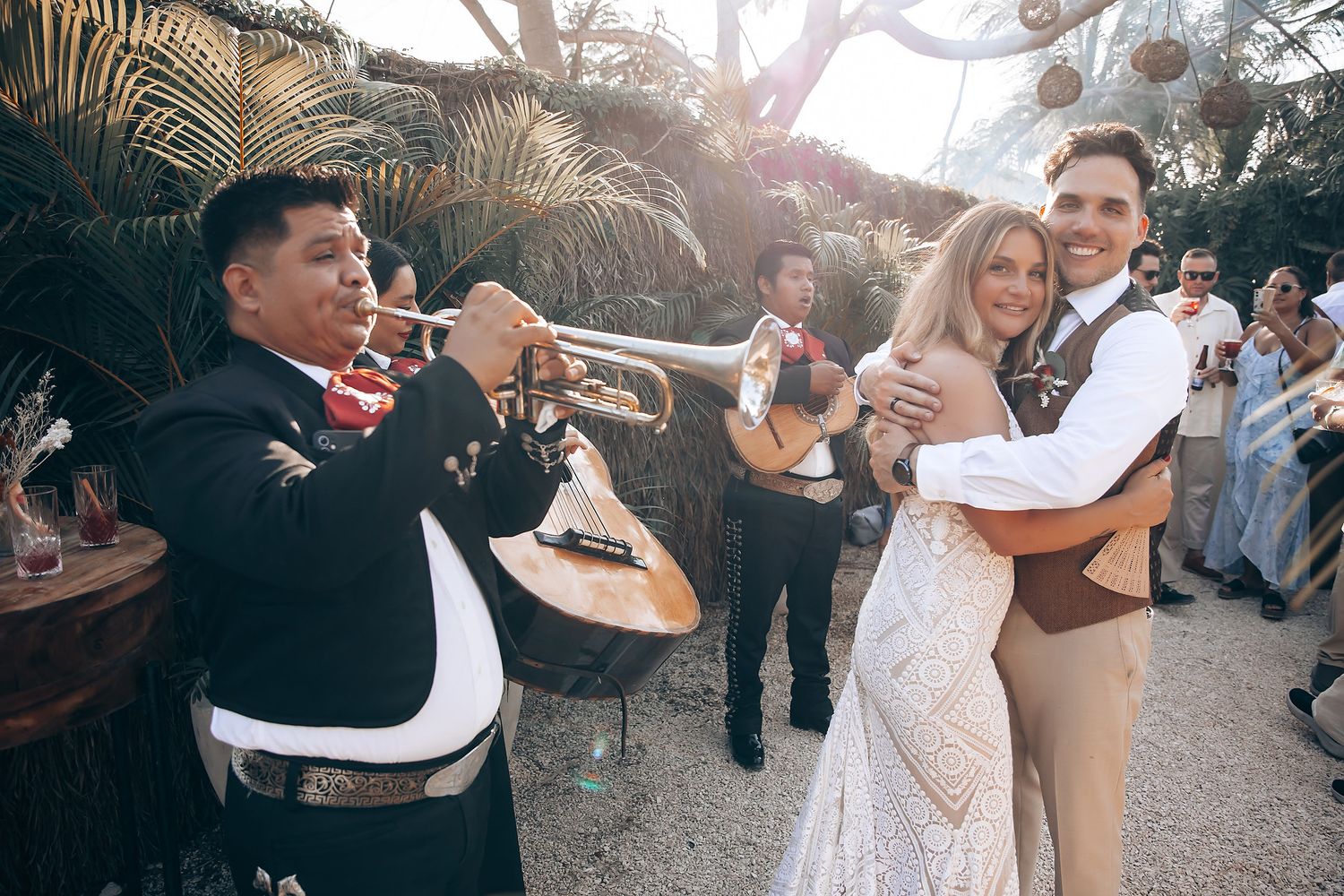 A couple dancing together at an outdoor wedding celebration during golden hour.