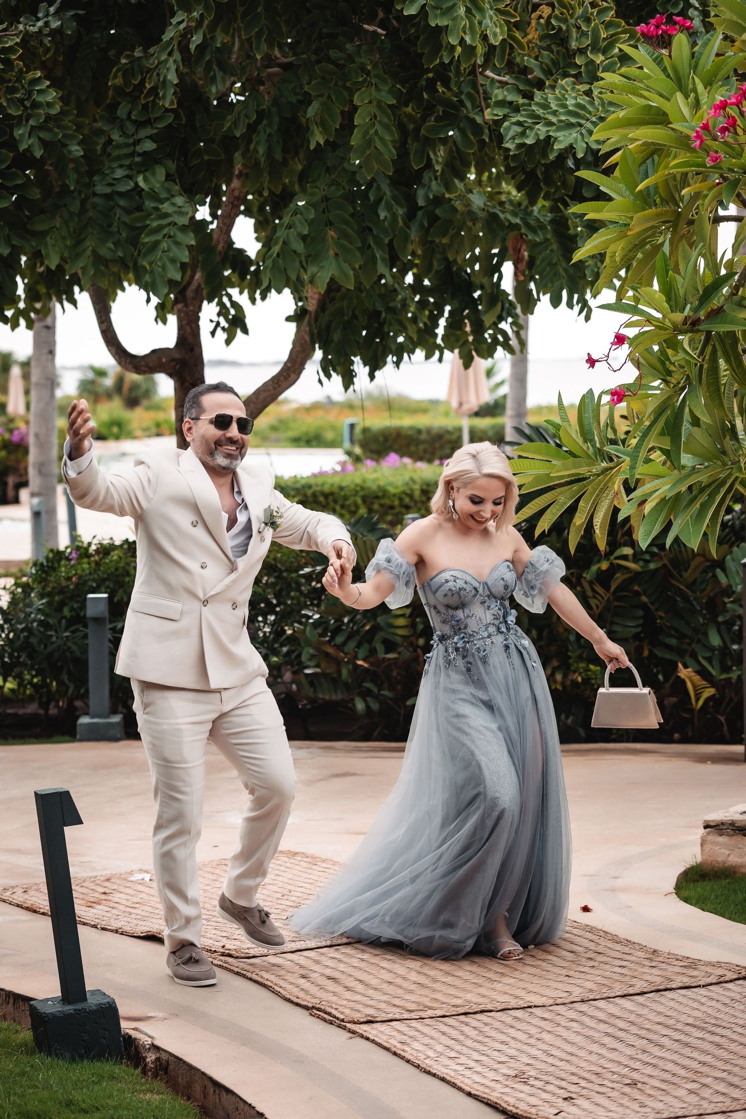Wedding party members in formal attire playfully posing on a brick pathway.