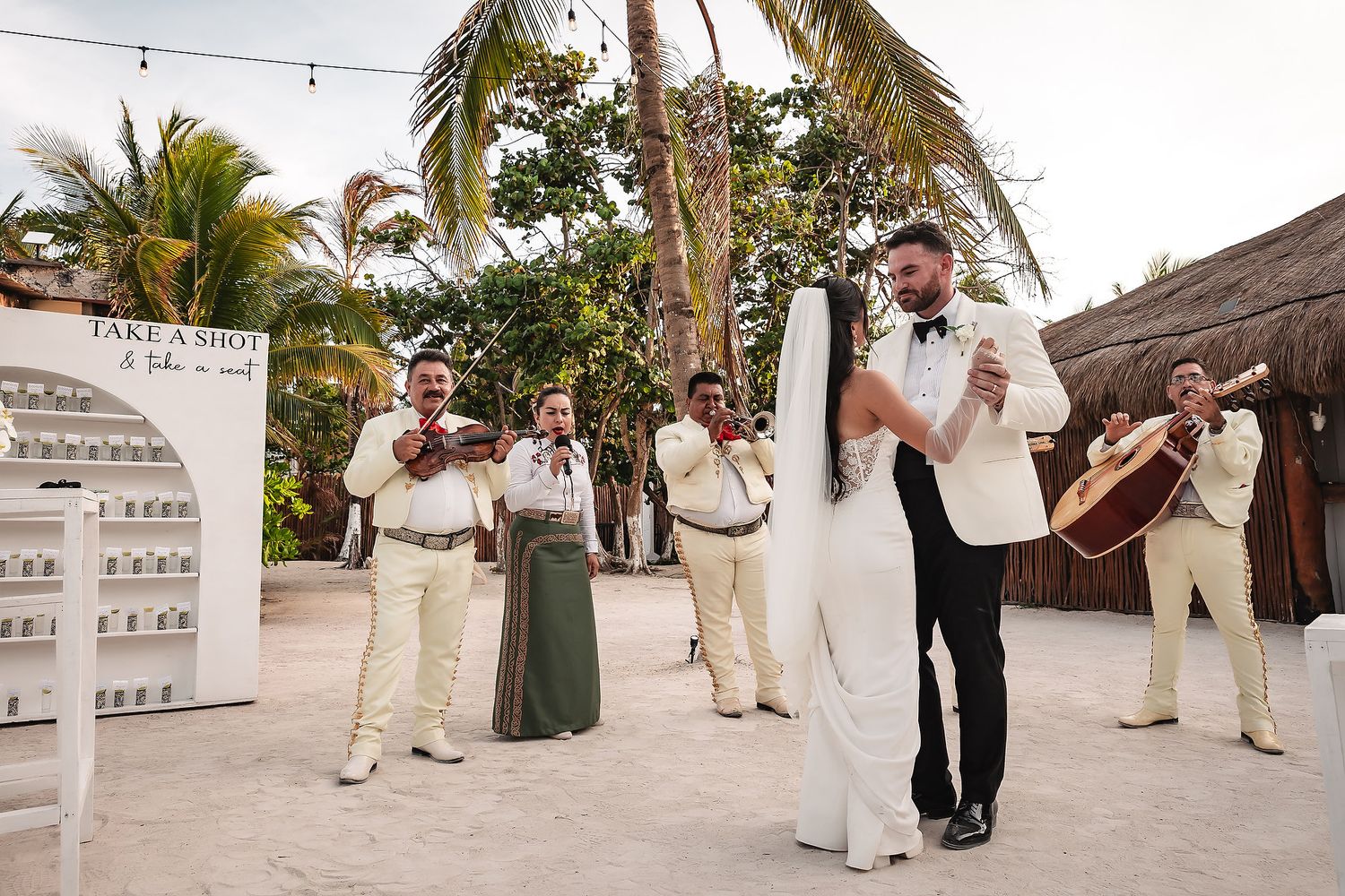 Live band performing at beach wedding with music stand and tropical backdrop.