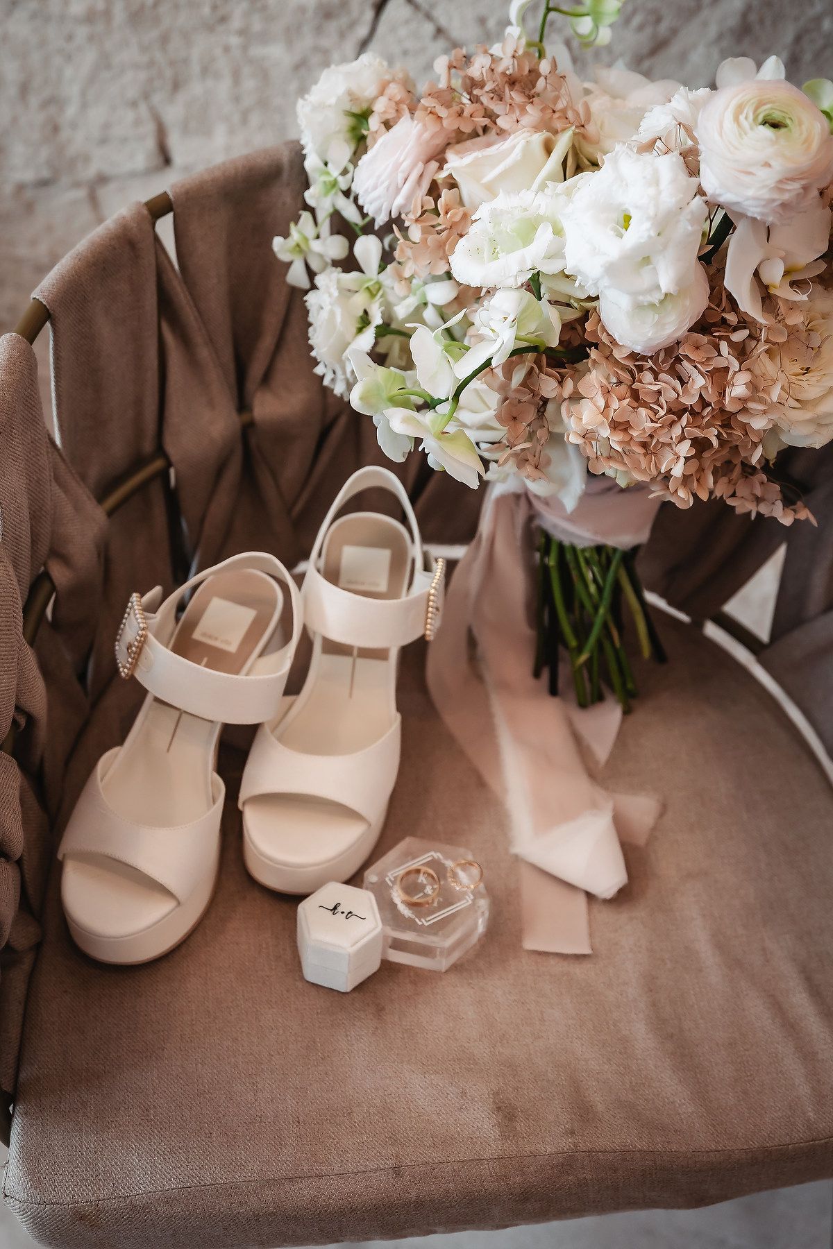 Elegant cream-colored bridal shoes displayed with soft pink and white floral bouquet.