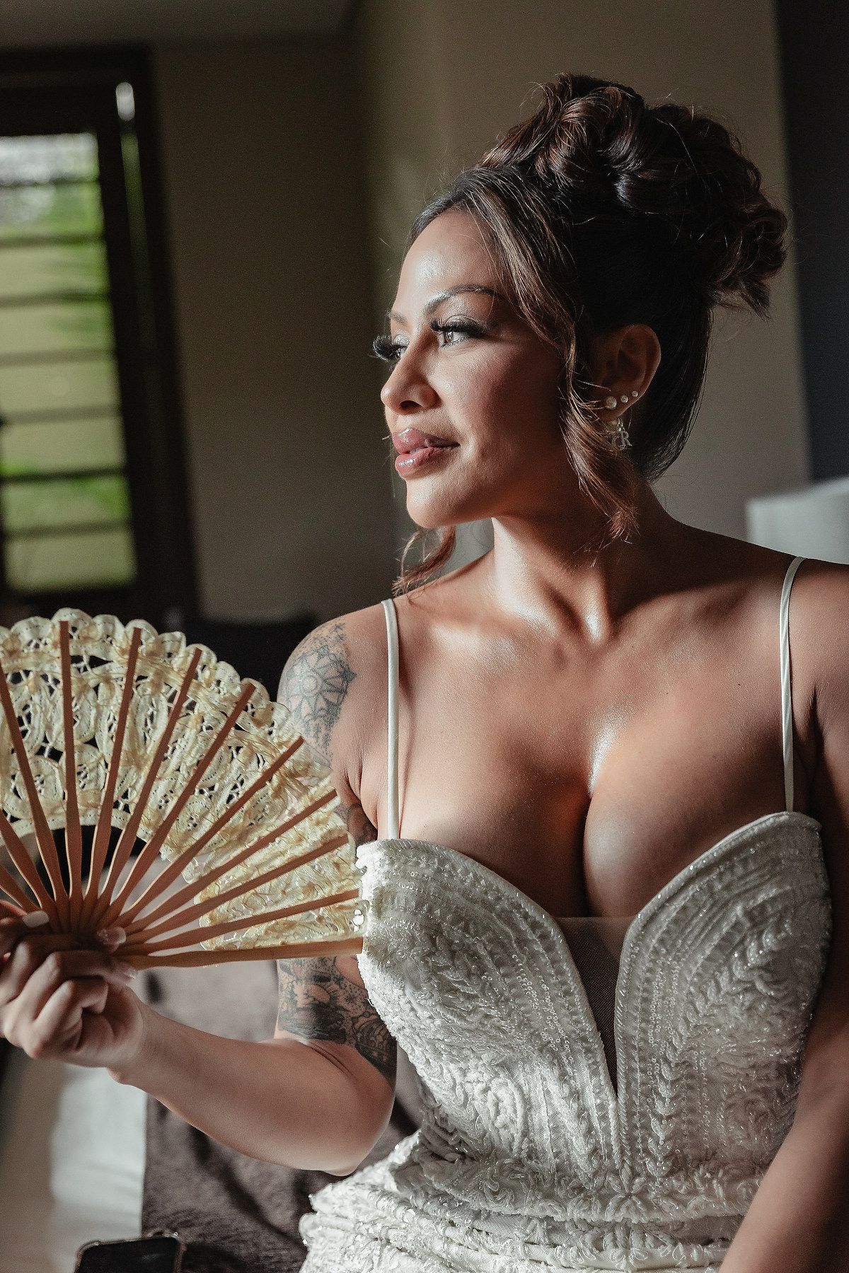 A bride in a white beaded wedding dress poses with an ornate gold and white decorative fan in multiple artistic shots.
