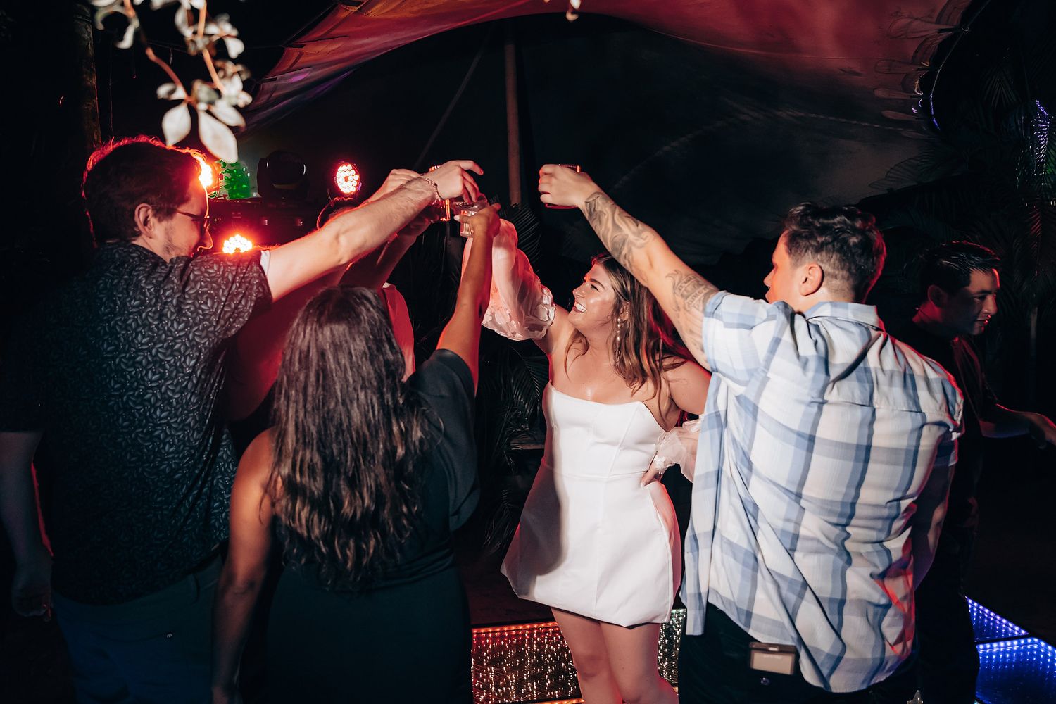 People dancing and having fun at a nightclub with colorful lighting and energetic atmosphere.
