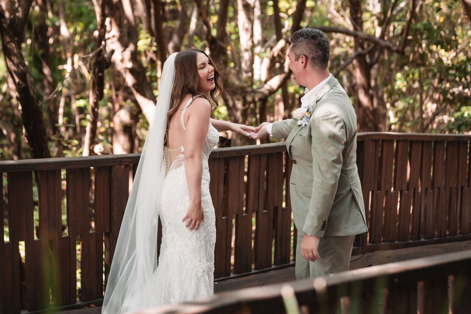 Romantic wedding moments captured on a wooden boardwalk surrounded by tropical trees.