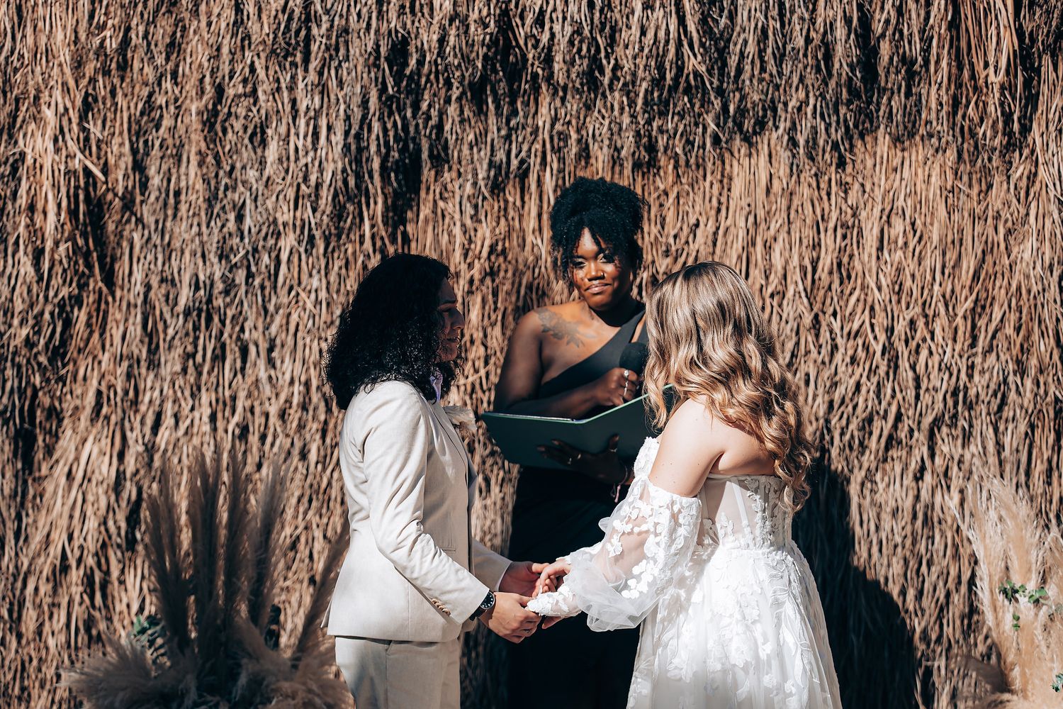 Wedding ceremony setup with rustic thatched roof and white decor.