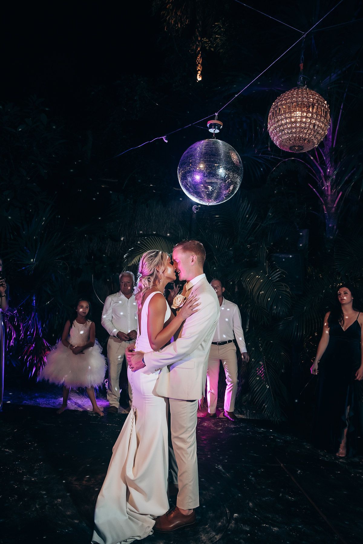 Couple dancing intimately under a purple disco ball at a wedding reception.