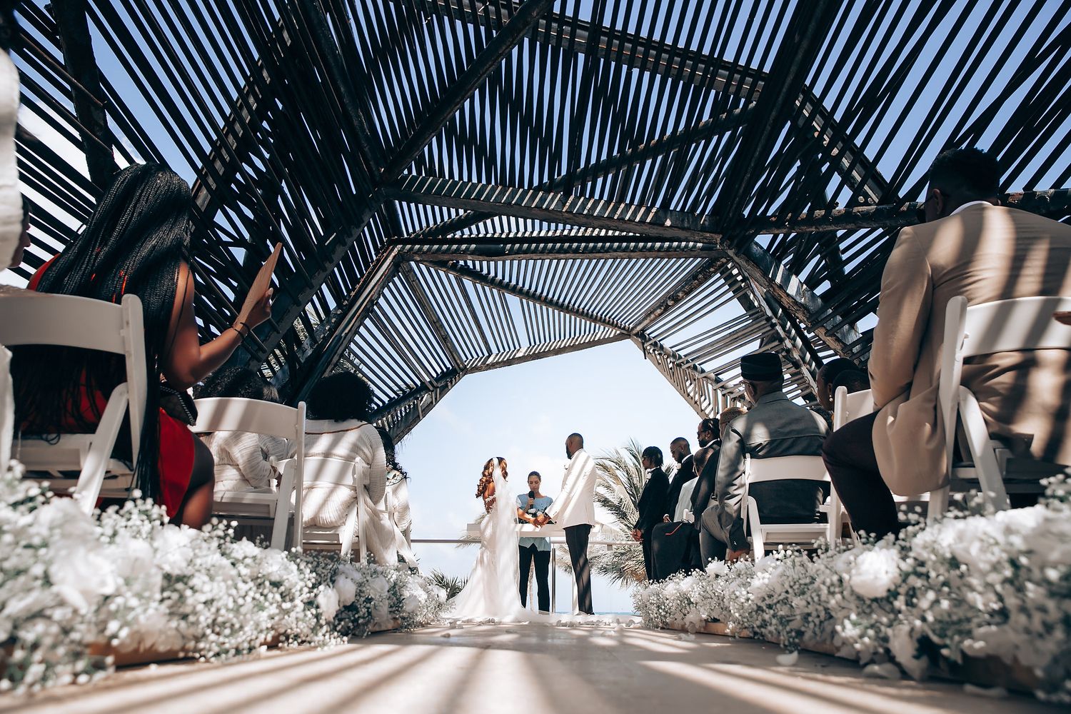 Modern wedding venue with geometric glass ceiling and white floral decorations creating an elegant architectural space.