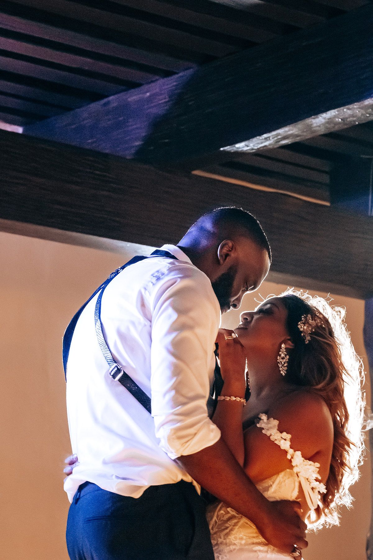 Romantic first dance moment captured in dramatic lighting at an indoor wedding reception.
