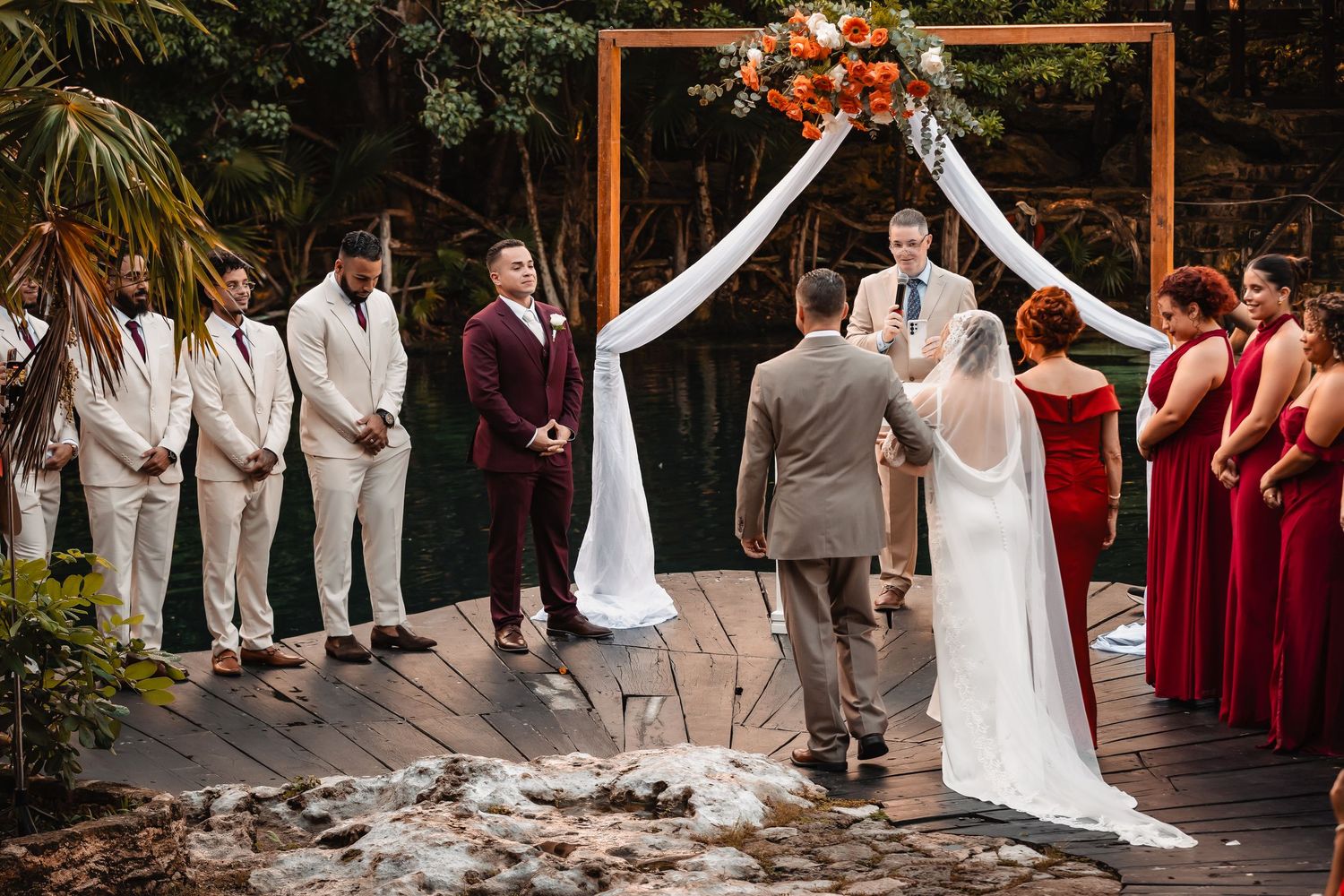 Wedding ceremony on rustic wooden deck with burgundy and white color scheme.