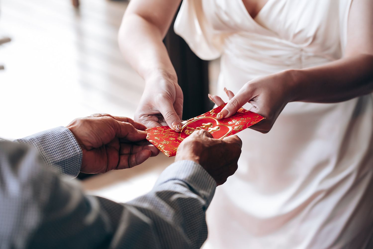 Hands exchanging traditional red envelopes during a wedding ceremony celebration.