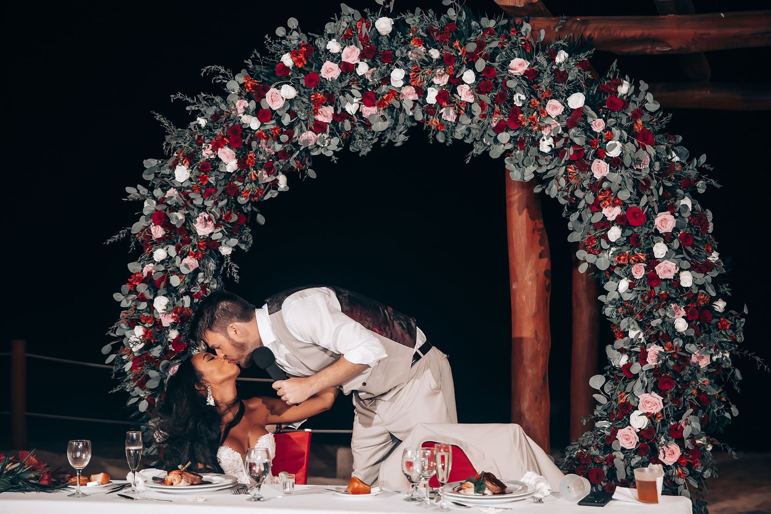 A couple in white outfits performs a choreographed dance sequence during a wedding reception.