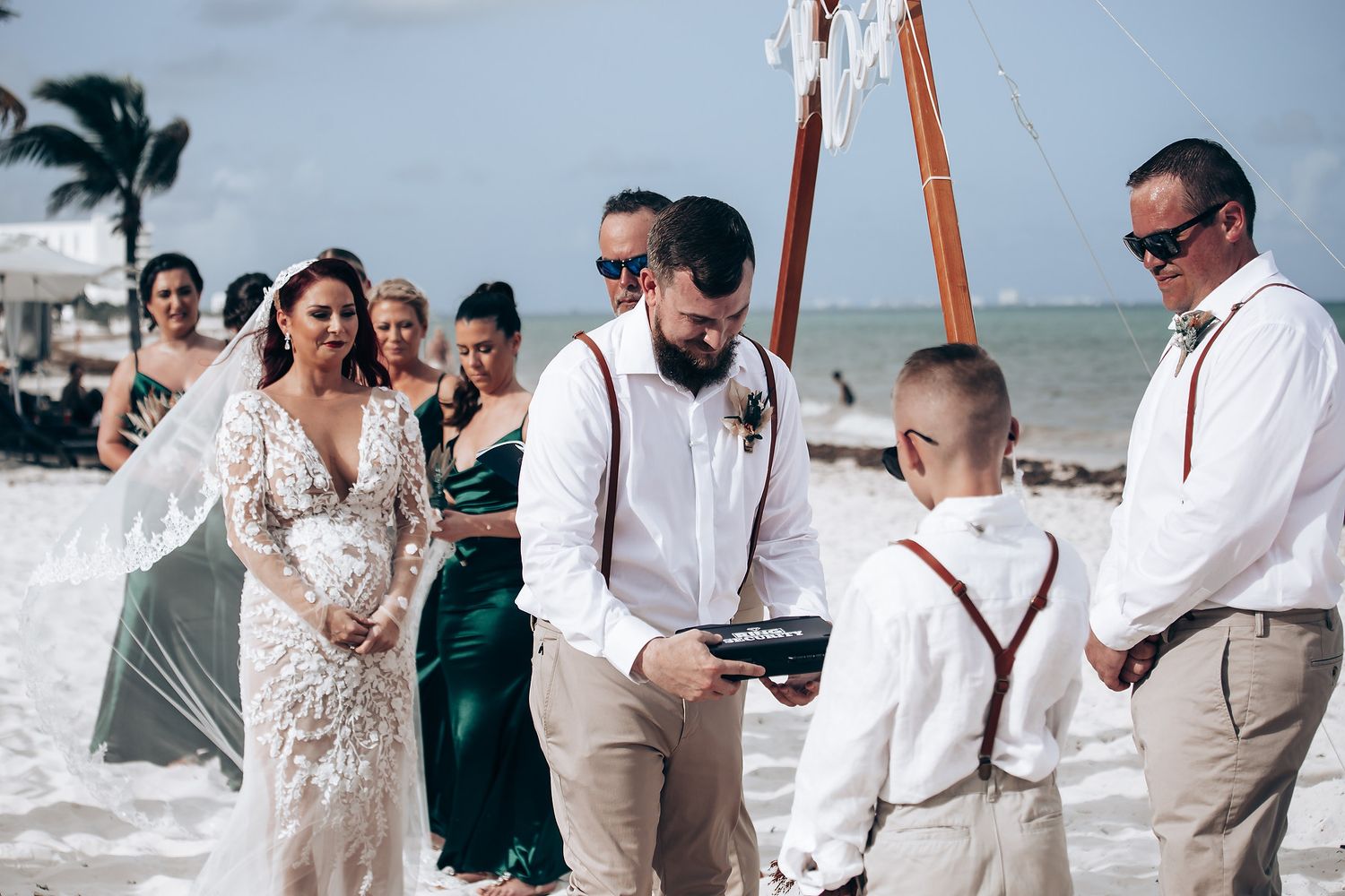 Beach wedding ceremony setup with wooden arch and white chairs on sandy shore.