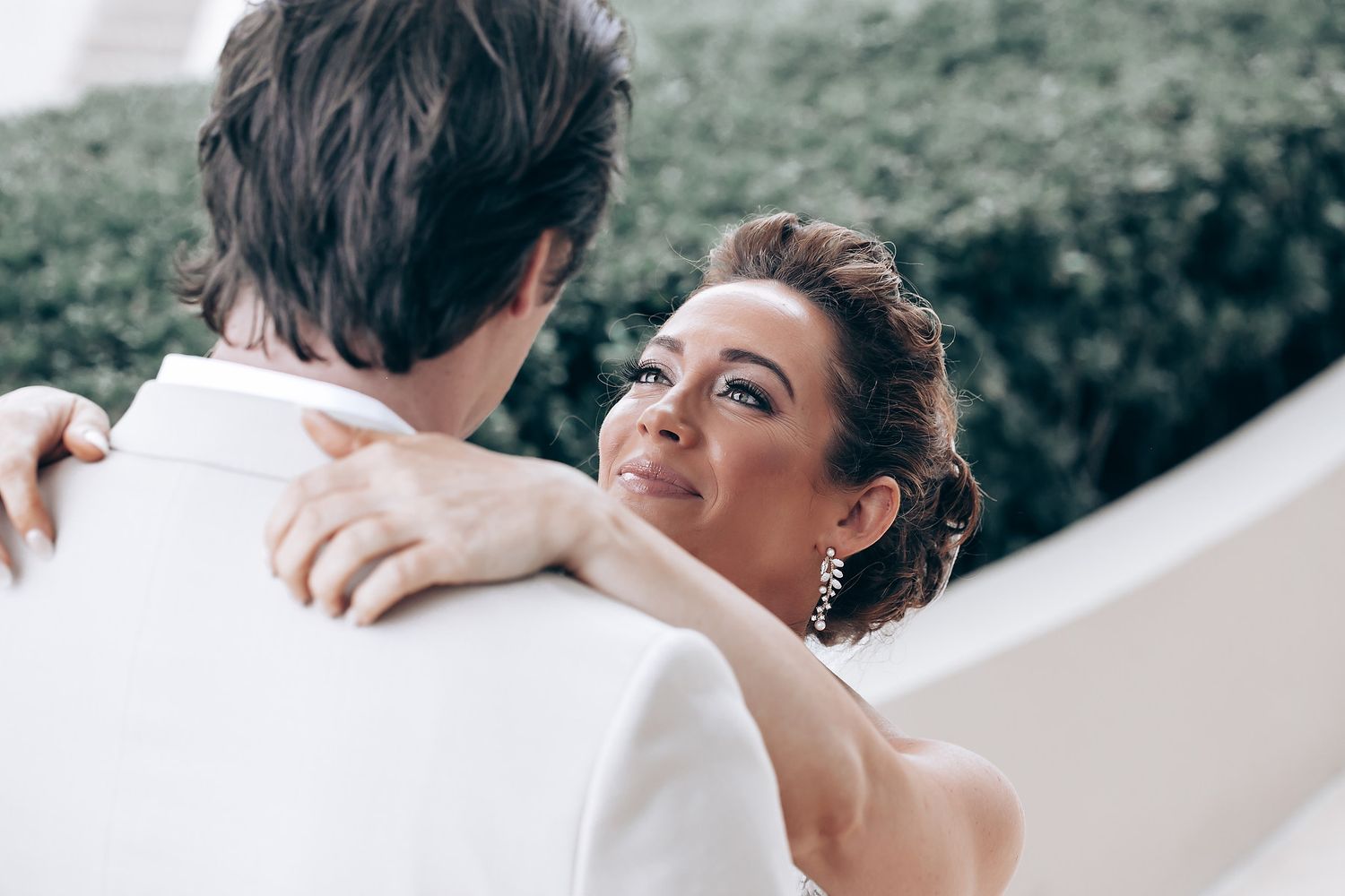 Intimate wedding moment captured during outdoor celebration with greenery backdrop.
