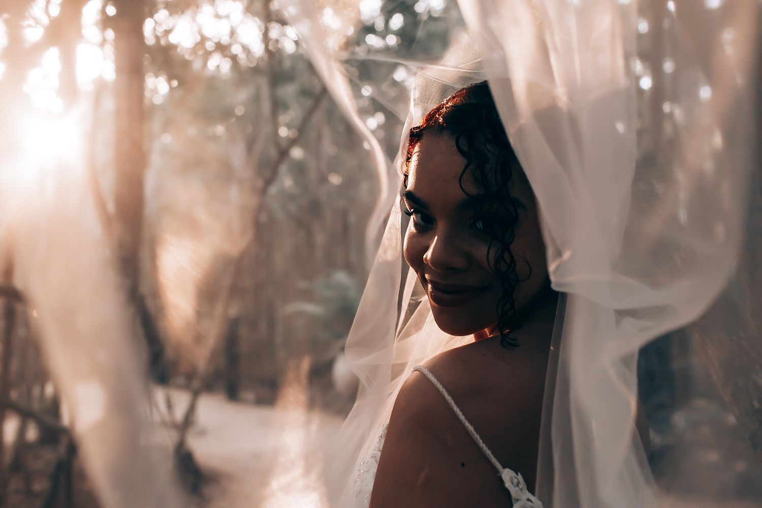Soft, ethereal wedding photography with natural sunlight streaming through trees.