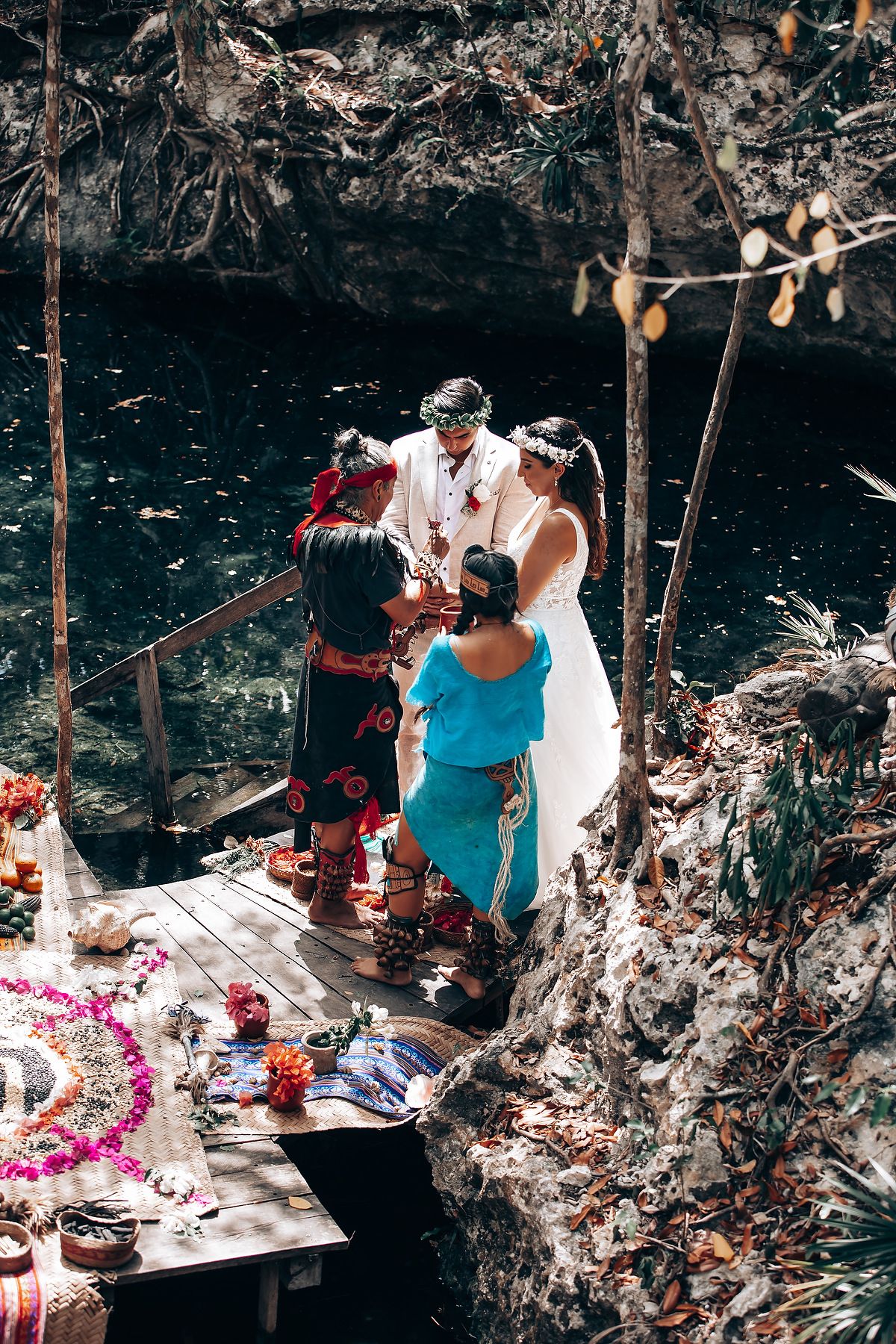 A traditional ceremony being performed on a wooden platform near dark waters with decorative elements.