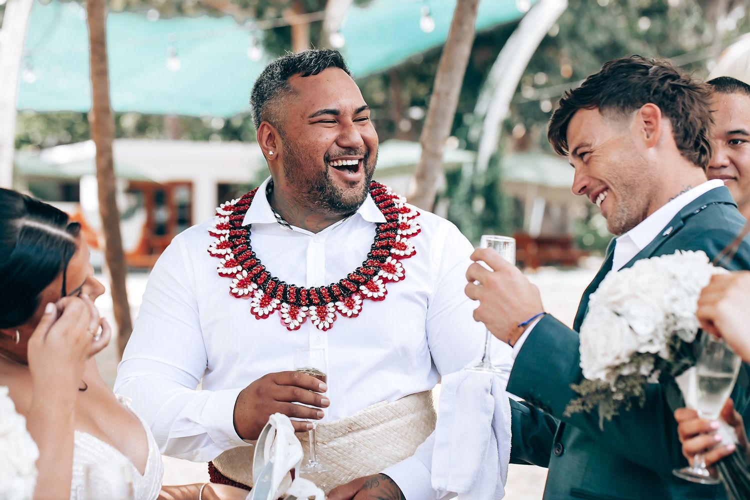 Wedding party celebrating with traditional Hawaiian leis during outdoor reception.