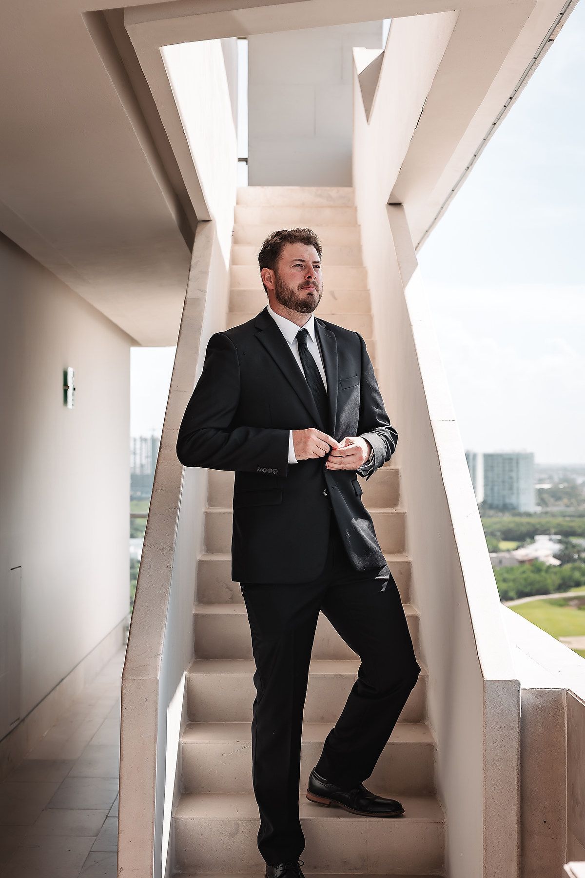 Person in formal attire posing in modern architectural setting with geometric white pillars.
