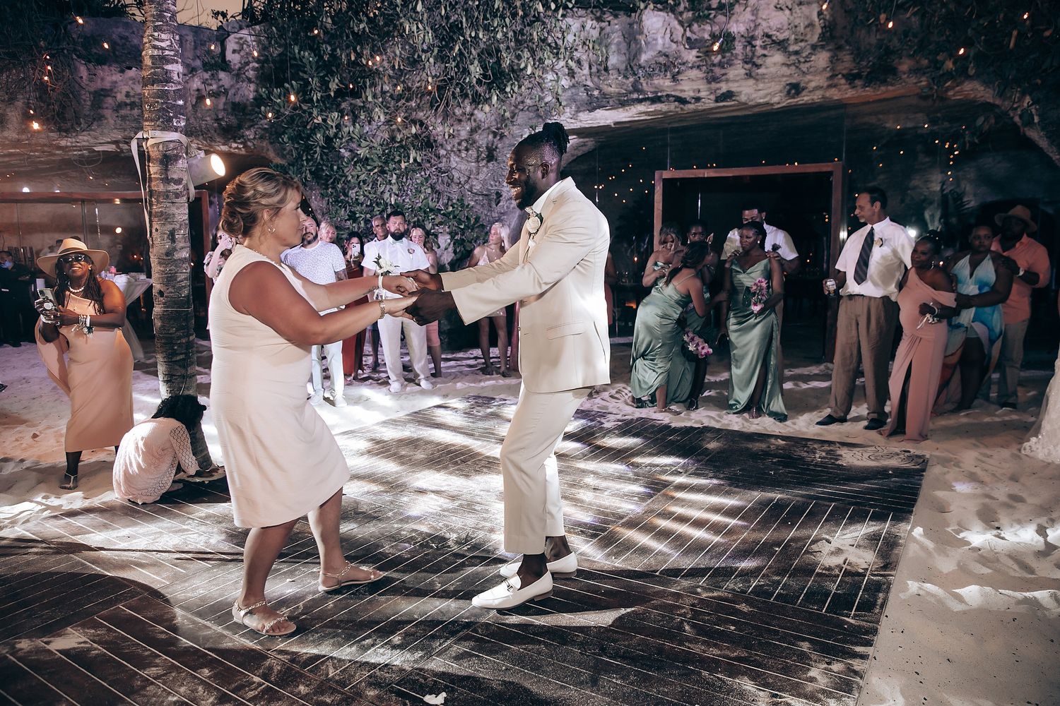 Wedding celebration with guests dancing on a patterned floor under natural lighting.