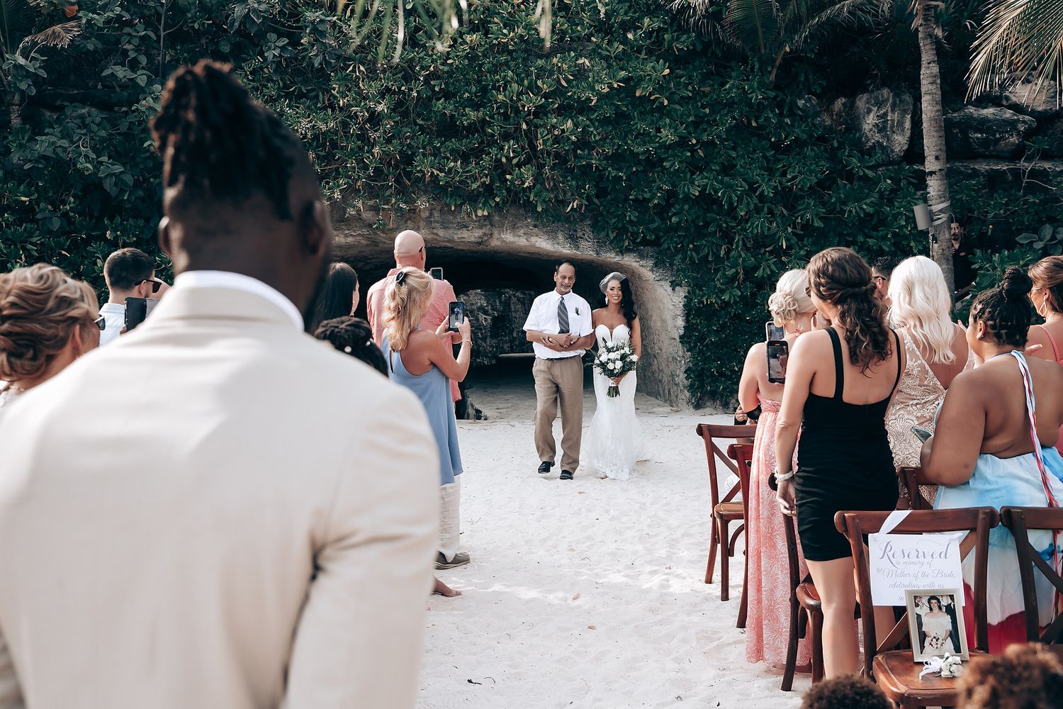Wedding guests seated outdoors for a ceremony surrounded by tropical landscaping.