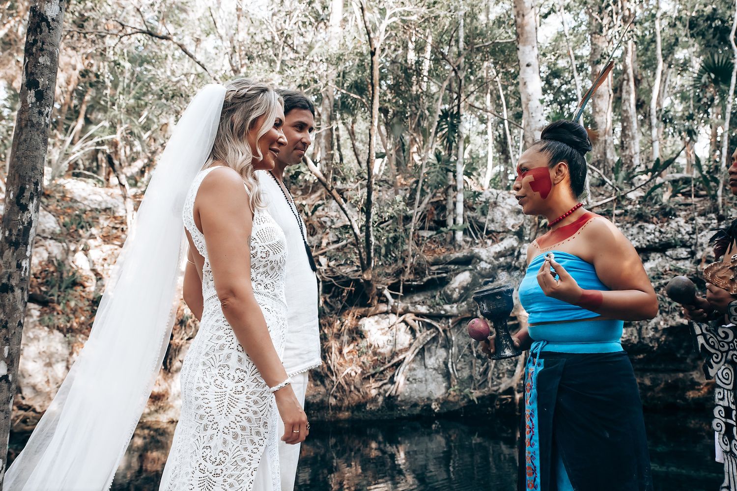 A couple embraces in a romantic outdoor photo session surrounded by sunlit trees and greenery.