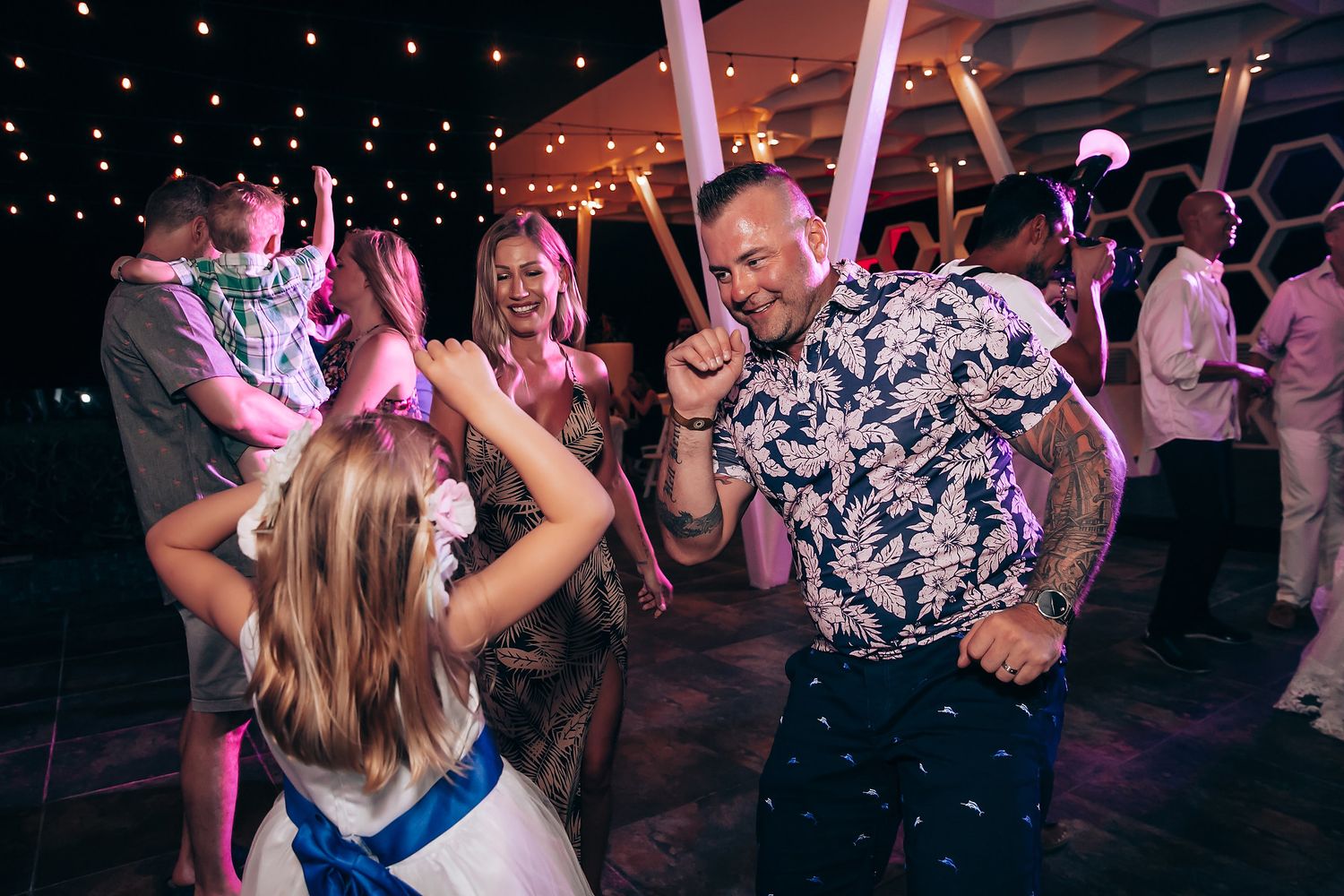 People dancing and celebrating at a nighttime party with colorful lighting and festive atmosphere.