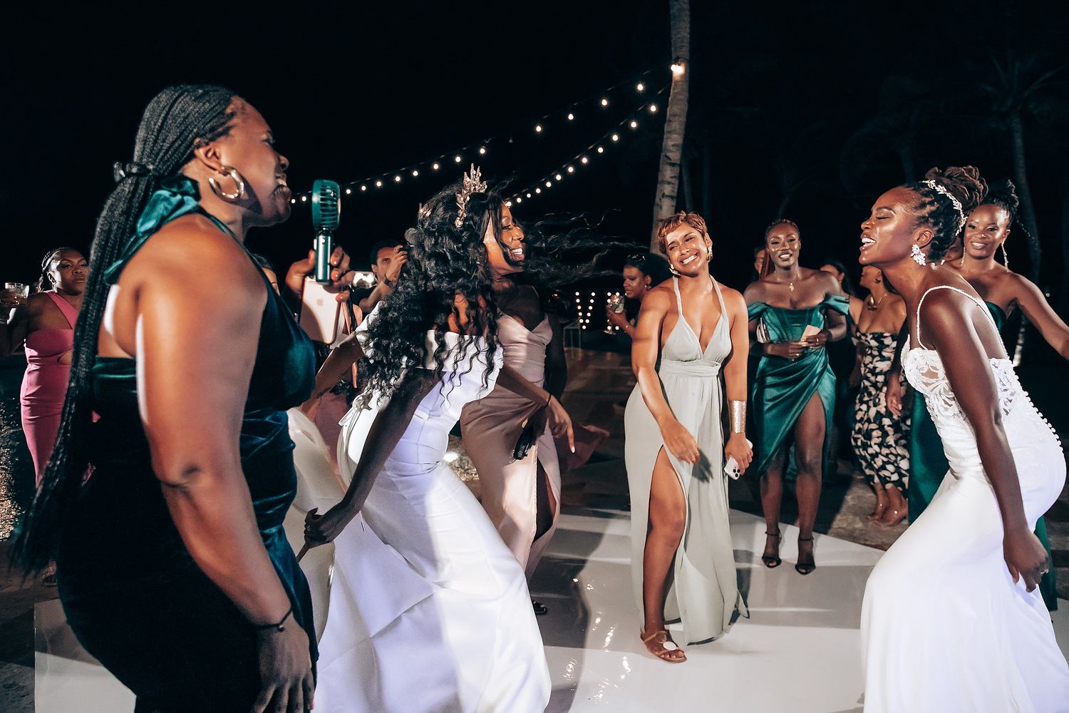 Wedding celebration at night with string lights and dancing guests.