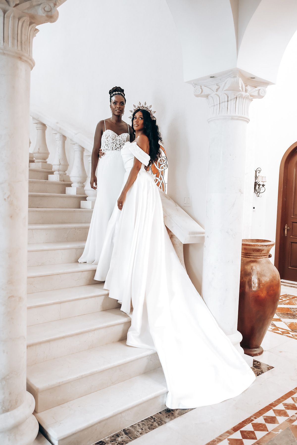 Elegant white wedding dress flowing down marble stairs with classical columns.
