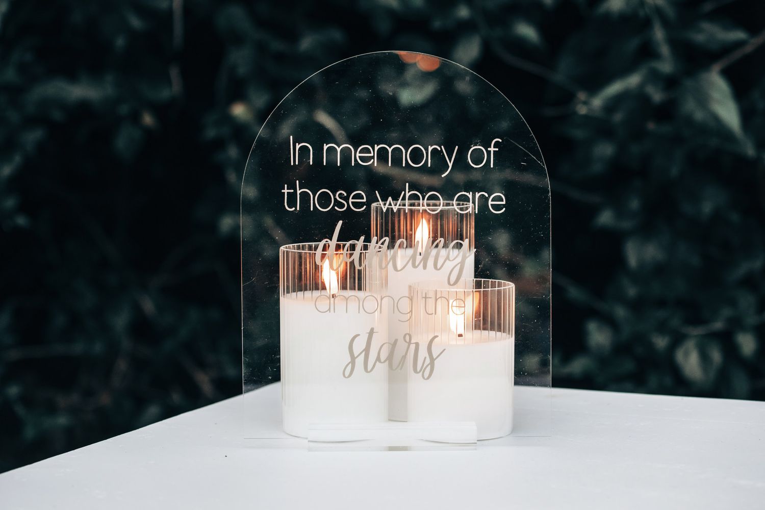 A memorial candle display with an acrylic sign reading In memory of those who are dancing among the stars.