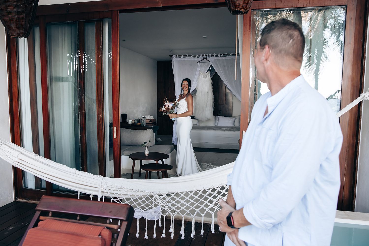 A couple embraces in an outdoor setting with a wooden fence in the background.
