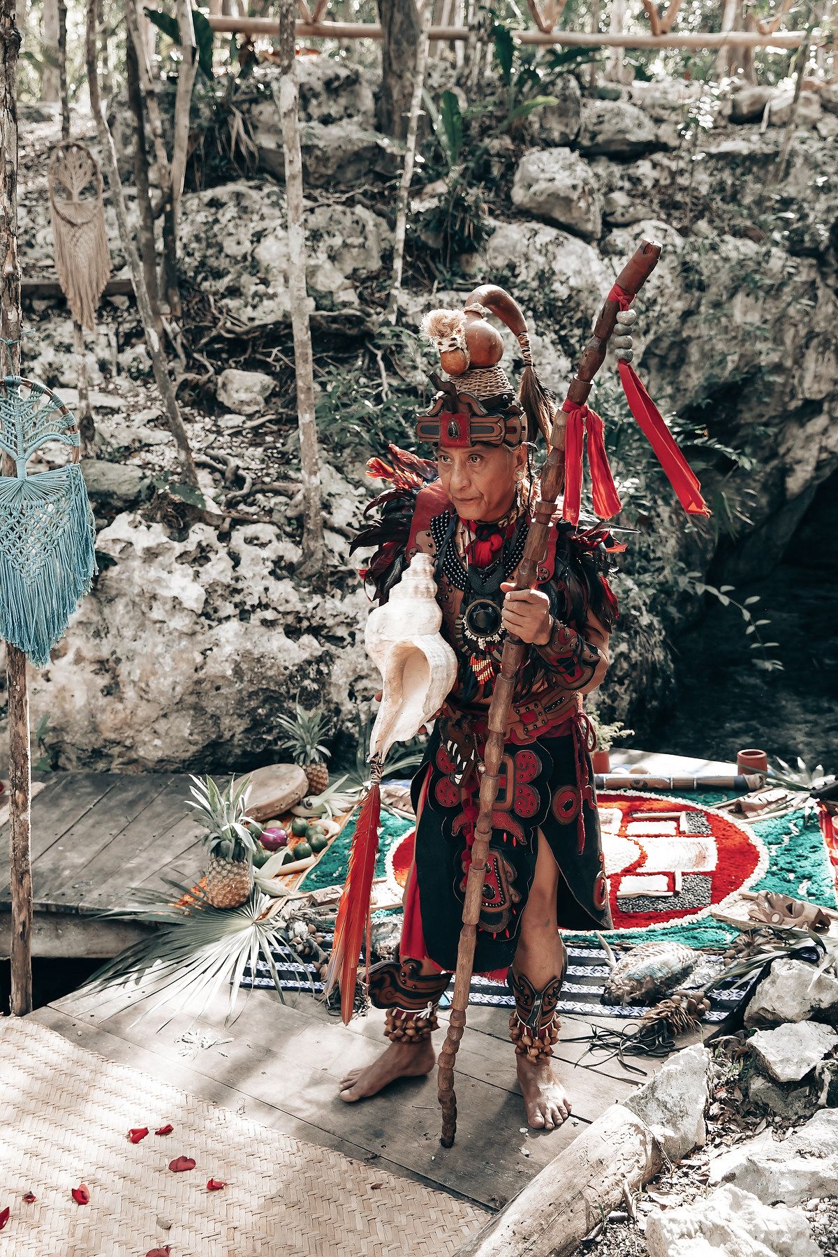 A colorfully dressed figure stands in a lush, forested environment.