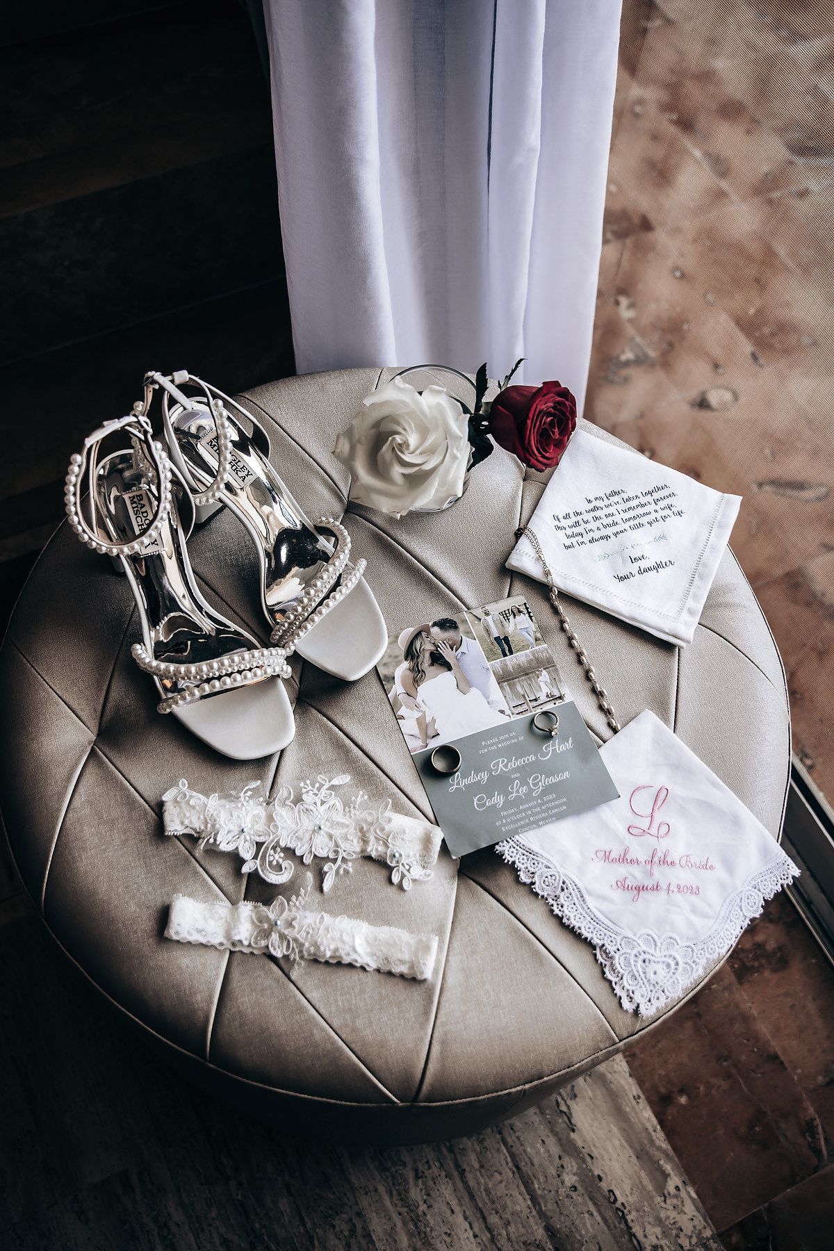 An assortment of bridal accessories including shoes, jewelry, and a rose is displayed on a table.