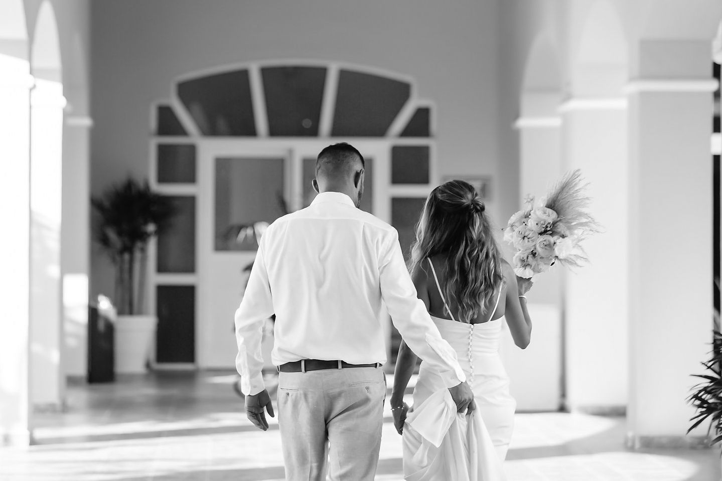 A couple walking together in a hallway with a large window.