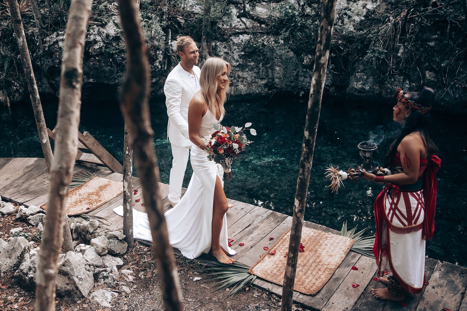Outdoor ceremony setup with white chairs and tropical decorations in a lush garden setting.