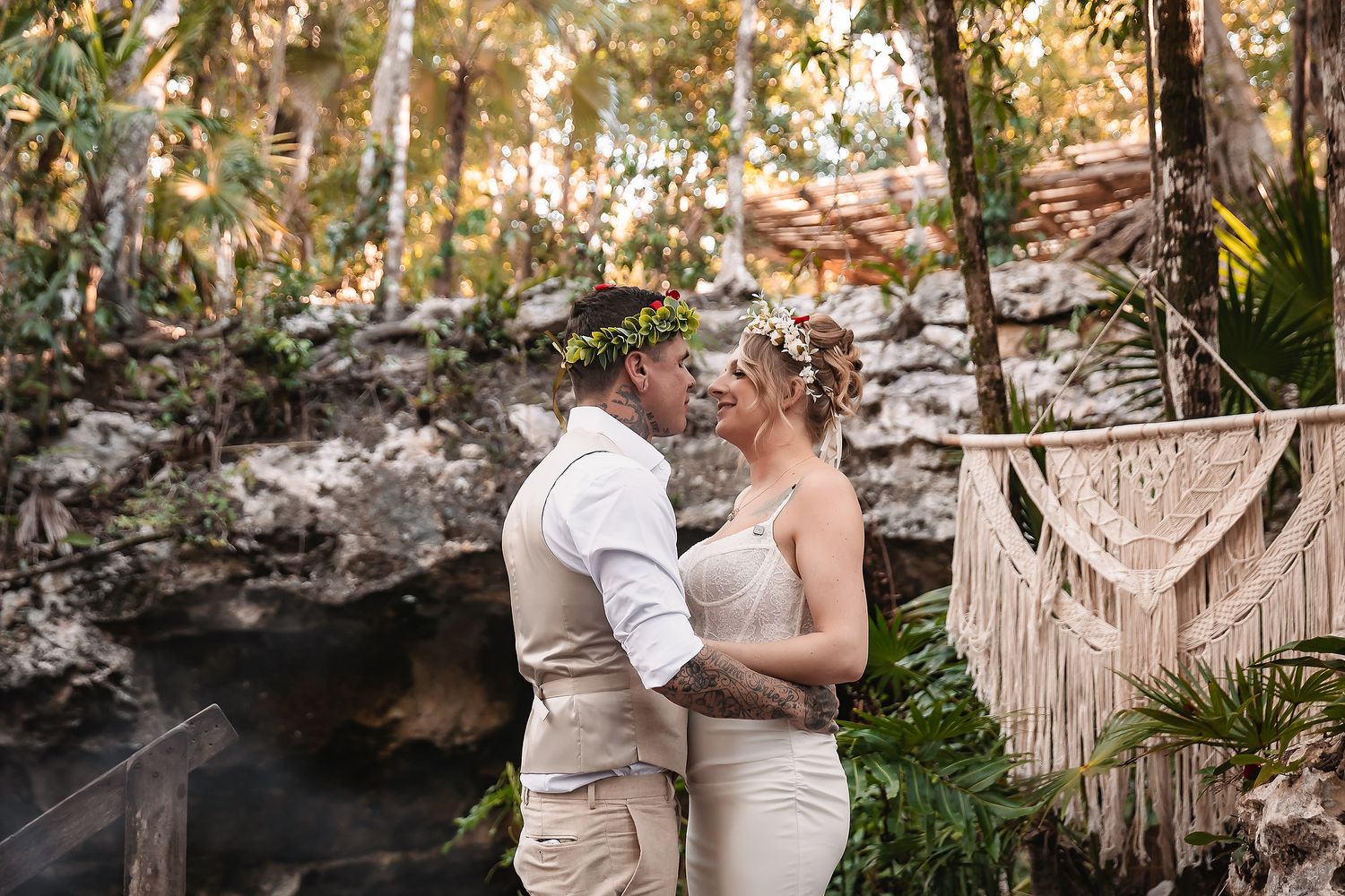 Couple in wedding attire sharing a romantic moment in a lush jungle setting with macrame decor.