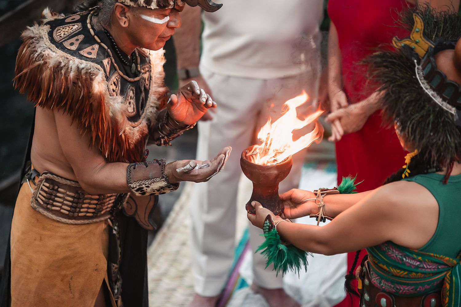 Indigenous performers in traditional attire participate in a ceremonial fire ritual during a cultural celebration.