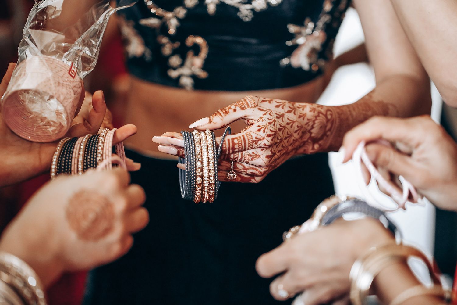 Traditional Indian bridal bangles and mehndi adorned hands during a wedding ceremony preparation.