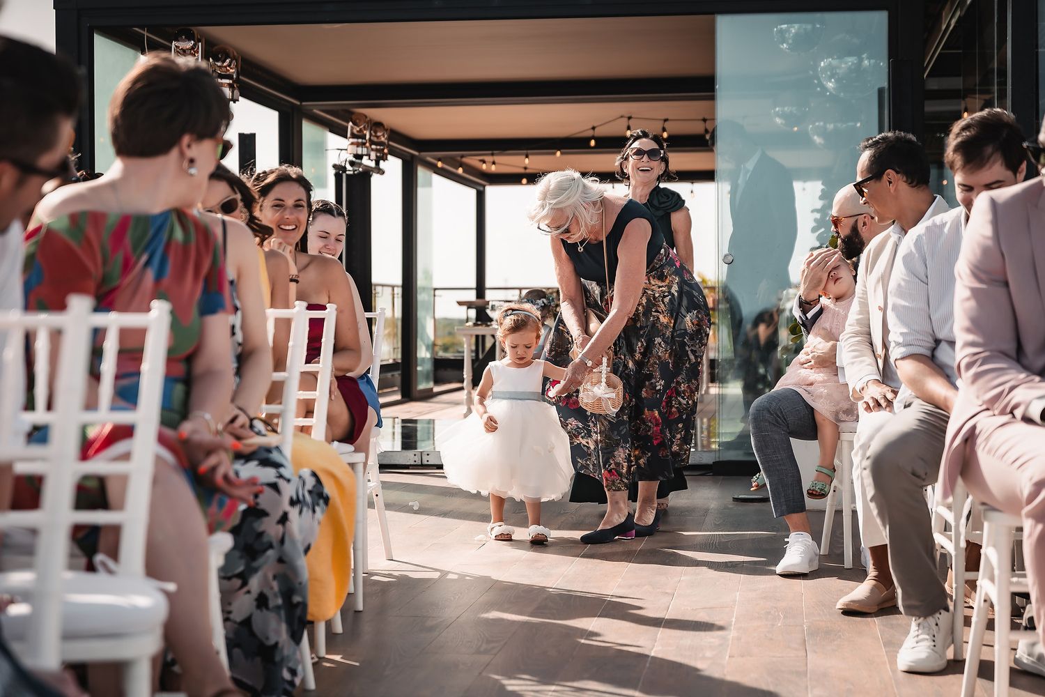 Wedding guests mingle at an elegant outdoor reception venue with white chairs and decorative elements.