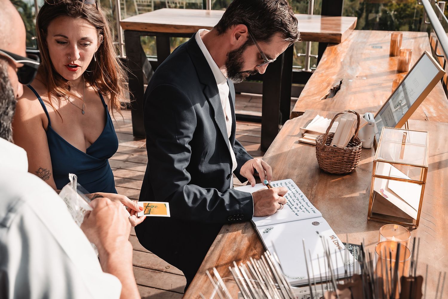 Wedding guests signing guestbook at elegantly decorated reception table.